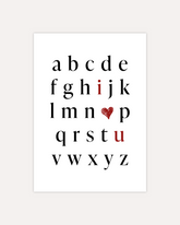 A postcard design showing the alphabet in mostly black letters. The letters "i" and "u" are red. In place of the letter "o" there is a red heart. The letters are arranged in a way that the red letters and heart read "I love you". The design is shown on a beige background.