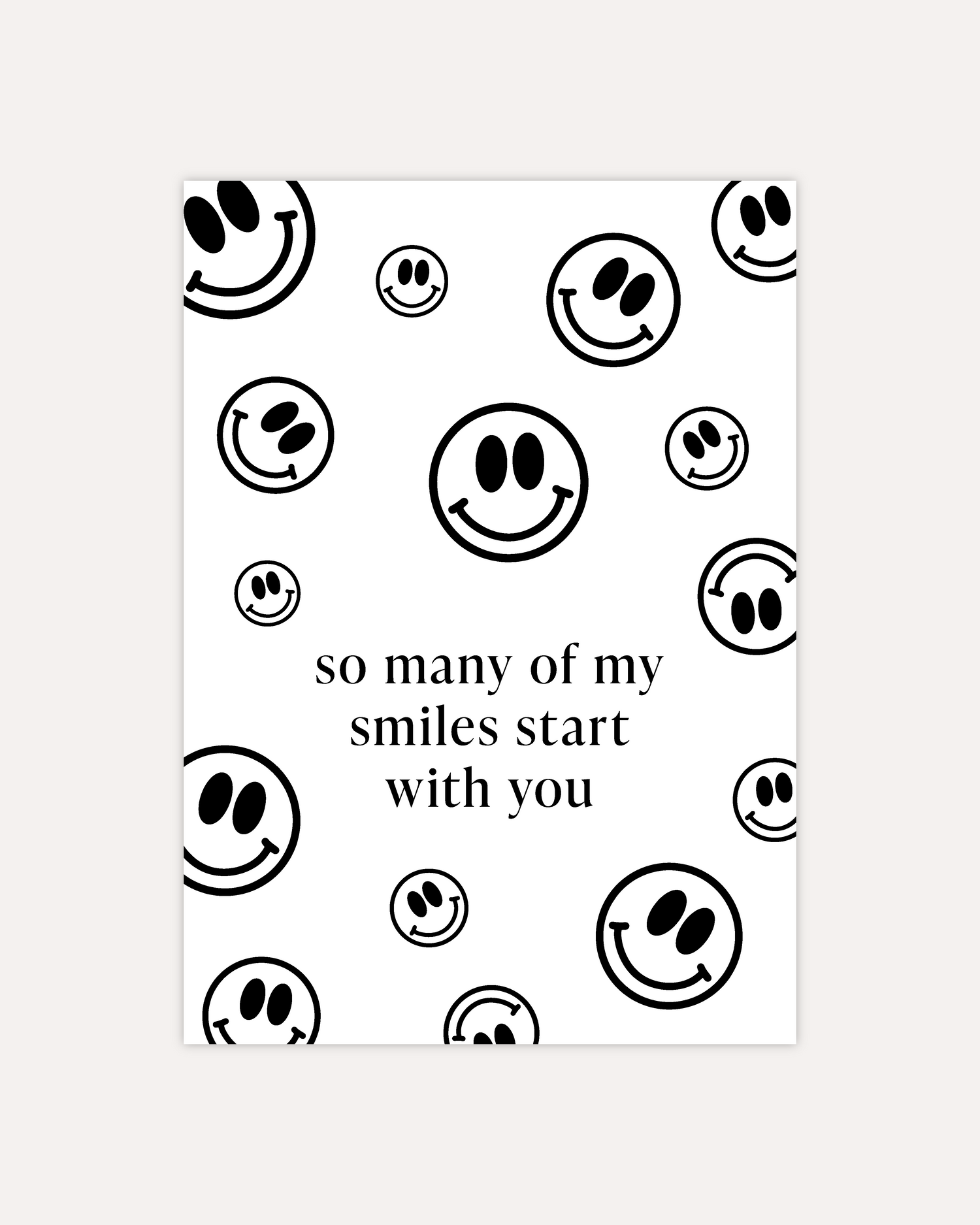 A postcard design consisting of many smiley faces in varying sizes and directions and some text in the middle saying &quot;so many of my smiles start with you&quot;. The design is shown on a beige background.