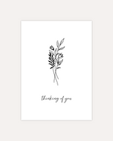 A postcard design showing a line art drawing of some flowers and leaves with a line of cursive writing below, that says "thinking of you". The design is shown on a beige background.